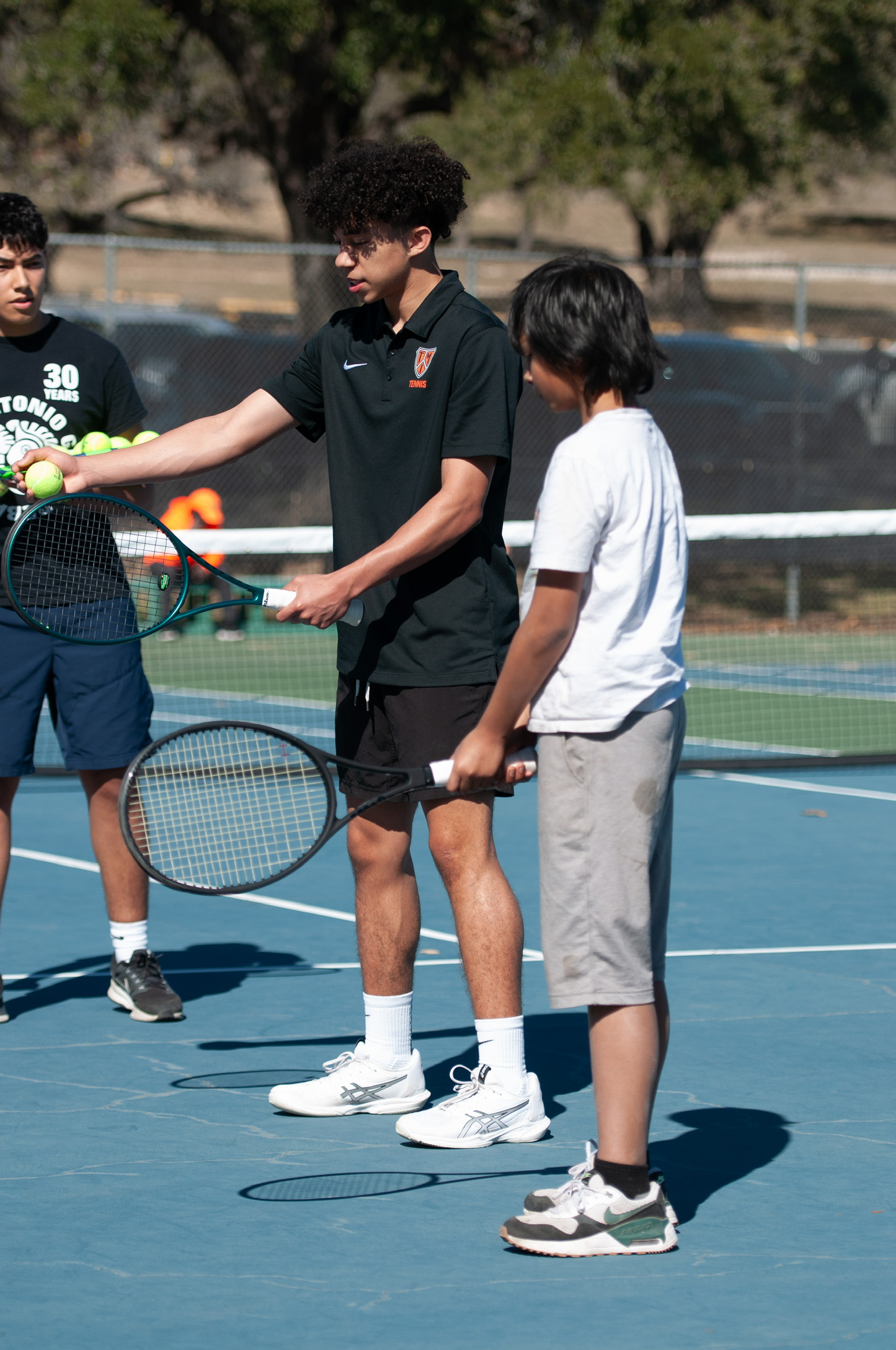 Philippe Jones coaching a young player at a Tennis4All clinic