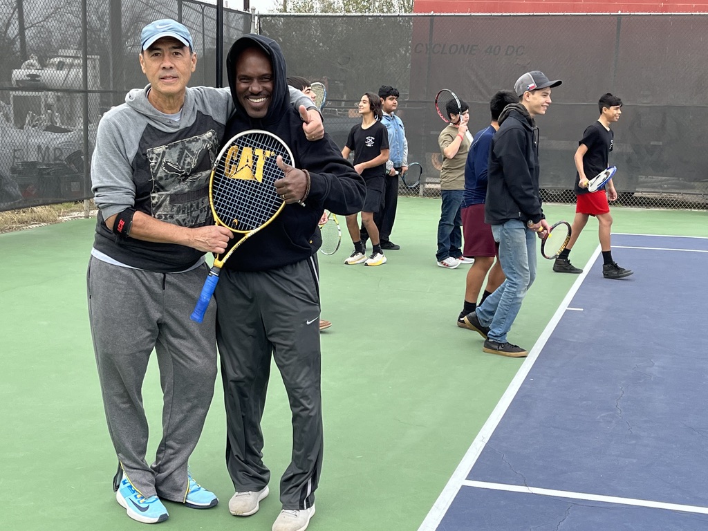 A volunteer coach handing a racket to a young player